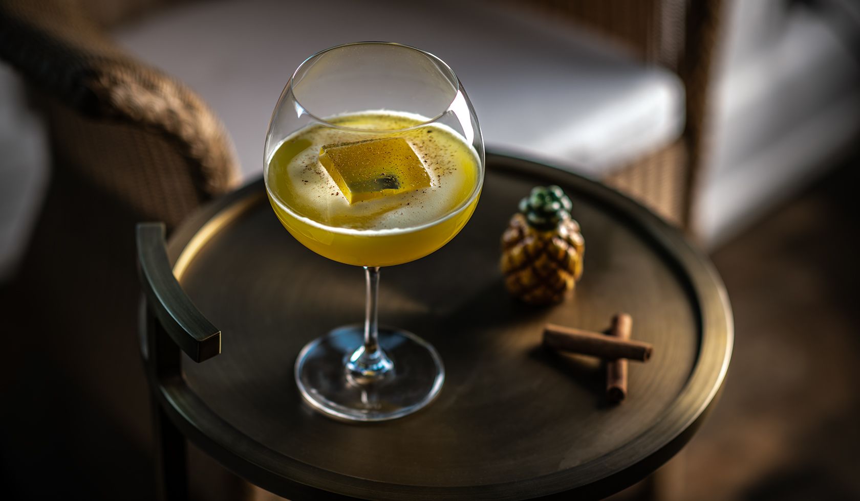 A Glass Of Yellow Liquid With A Toy Figurine On A Wood Surface