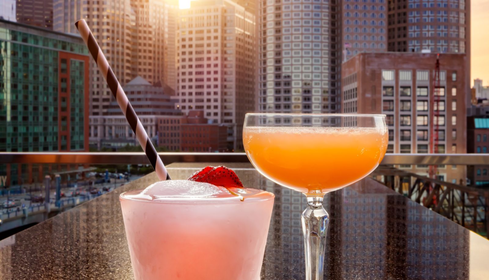 Two Glasses Of Drinks With Straws And A City Skyline In The Background